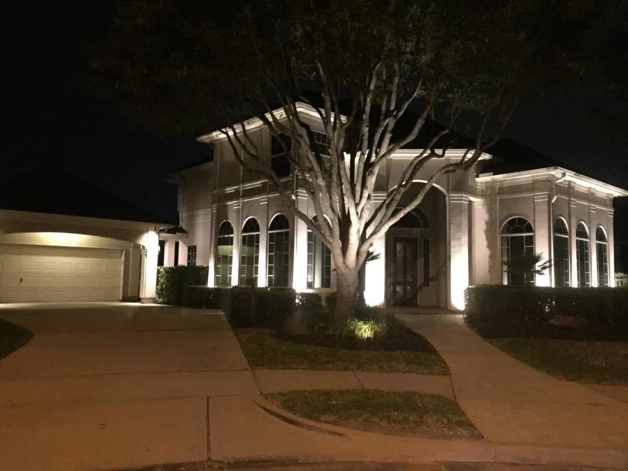 A house and tree lit up at night with different types of landscape lighting