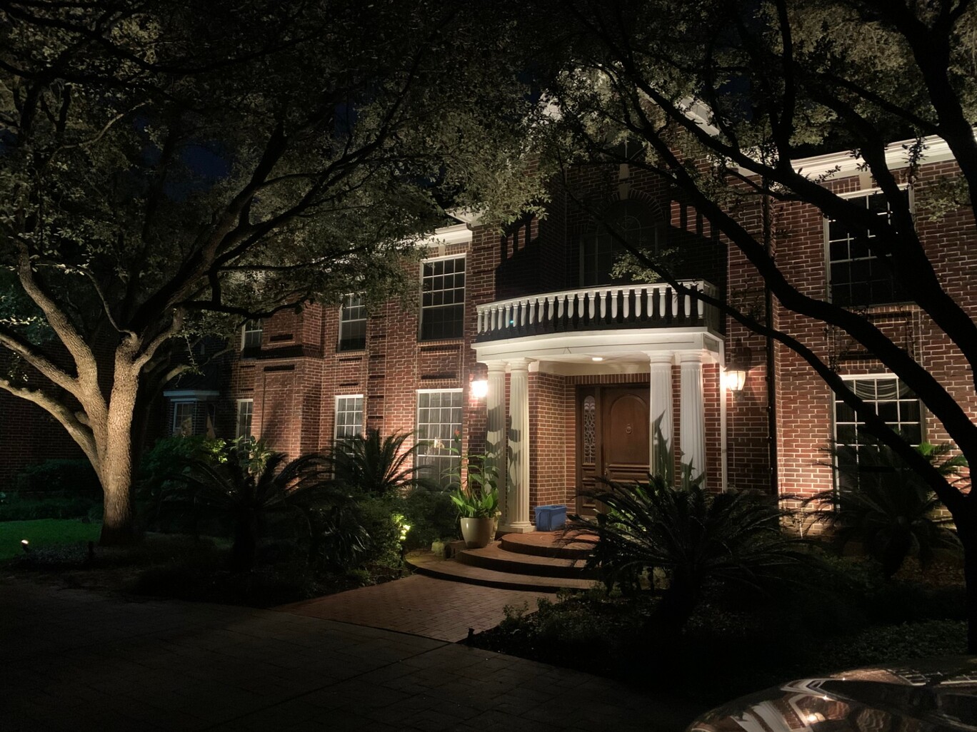 LED light maintenance lights up this two story brick house with white columns
