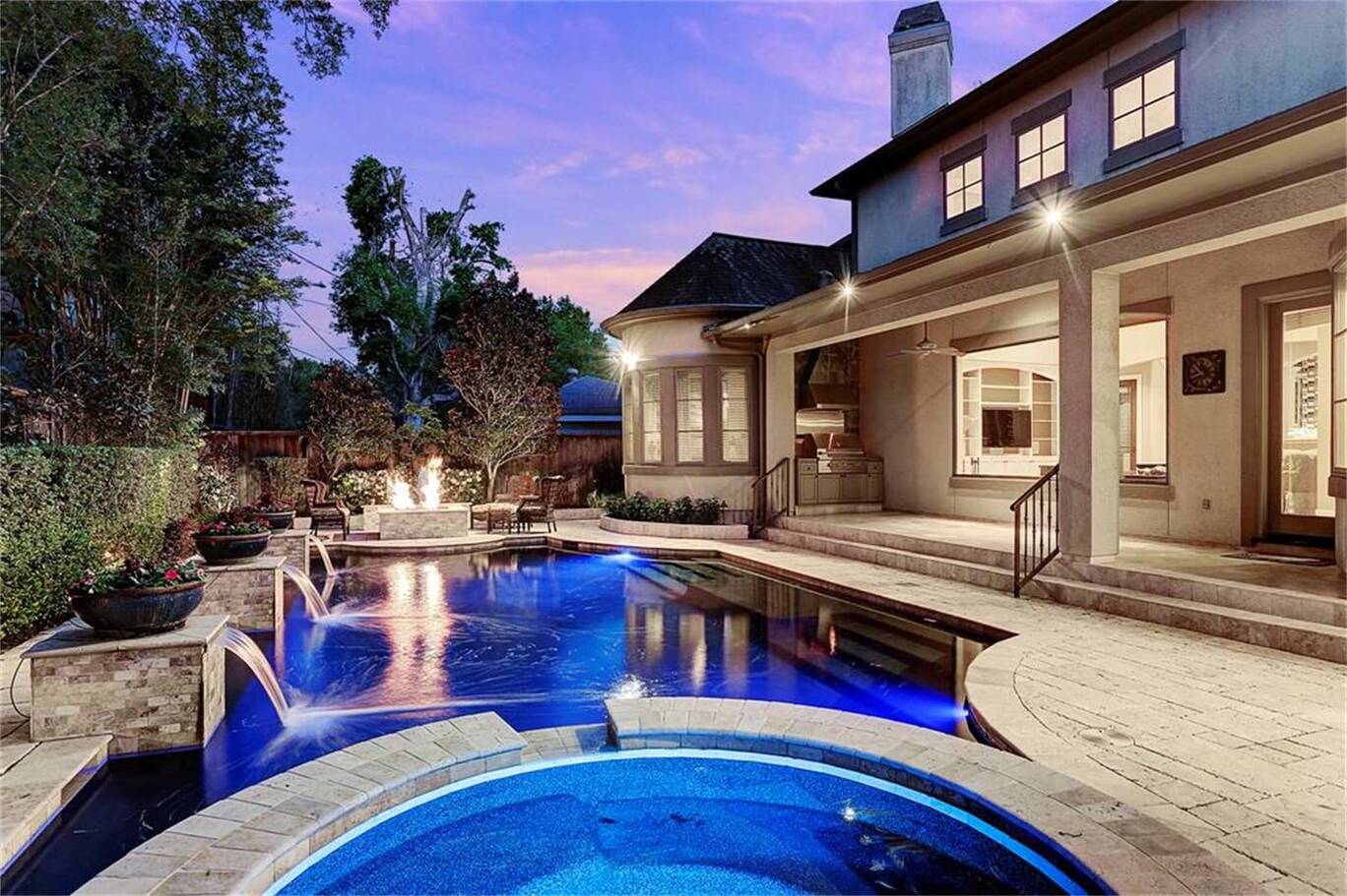 A house with a square and circular purple blue pool being illuminated by moonlight outdoor lighting