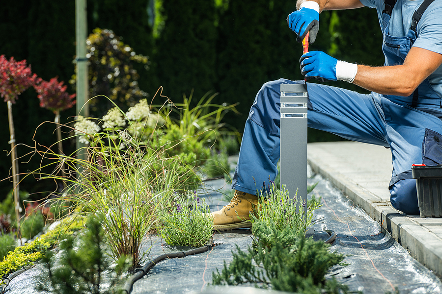 Technician Performing Outdoor Lighting Maintenance on ground fixture