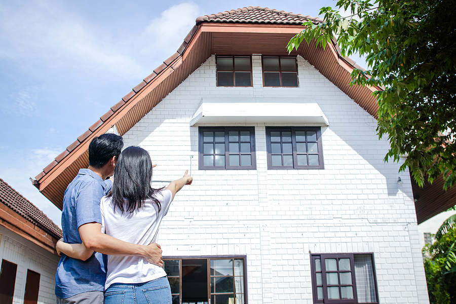First time home owner couple looking and pointing at home to add outdoor lighting