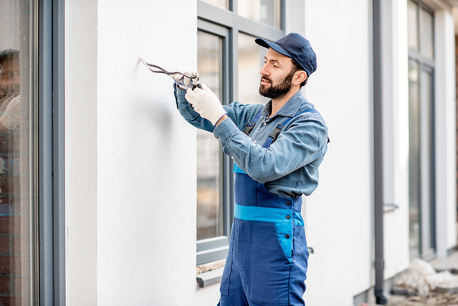 Builder checking electric wiring on the building facade for outdoor lighting. Maintain your outdoor lighting