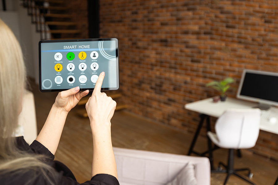 young woman using smart home app to control light turning on with tablet pc. Smart outdoor lighting