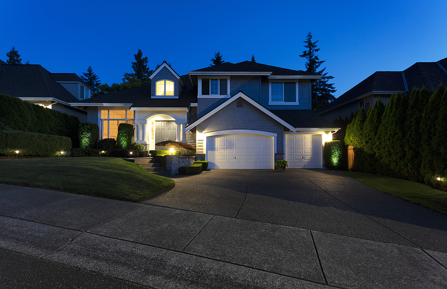 Modern suburban home exterior on a late summer evening with lights on yard and house. Front Yard