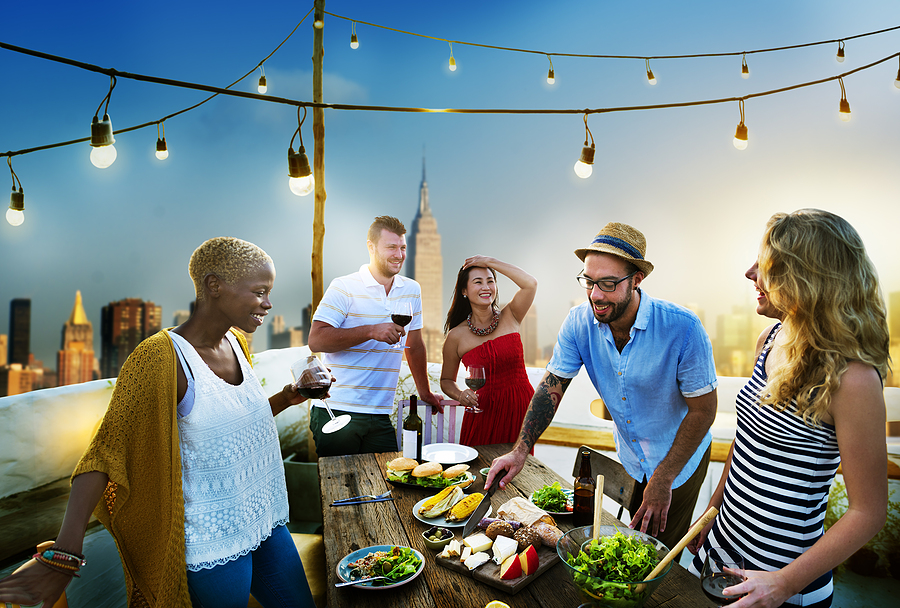 Group of friends having a summer party outside on patio/rooftop.
