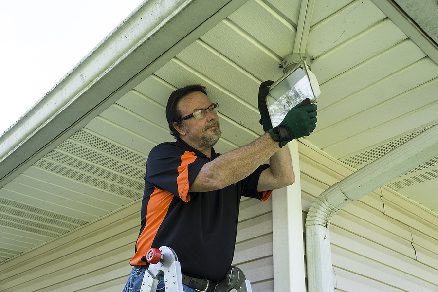 Electrician directing light downward to avoid light pollution for responsible commercial lighting. 