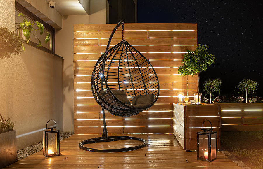 Stylish Backyard Garden with Wooden Porch with Wall and Planters Illuminated by Modern LED outdoor Lighting.