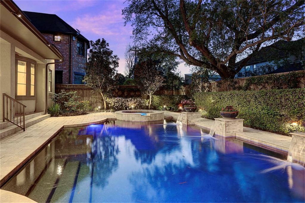 Home backyard with pool at sunset highlighting pool lighting.