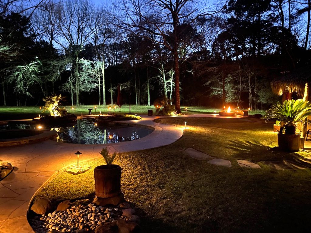 A homes backyard walkway at dusk highlighting landscape lighting design.