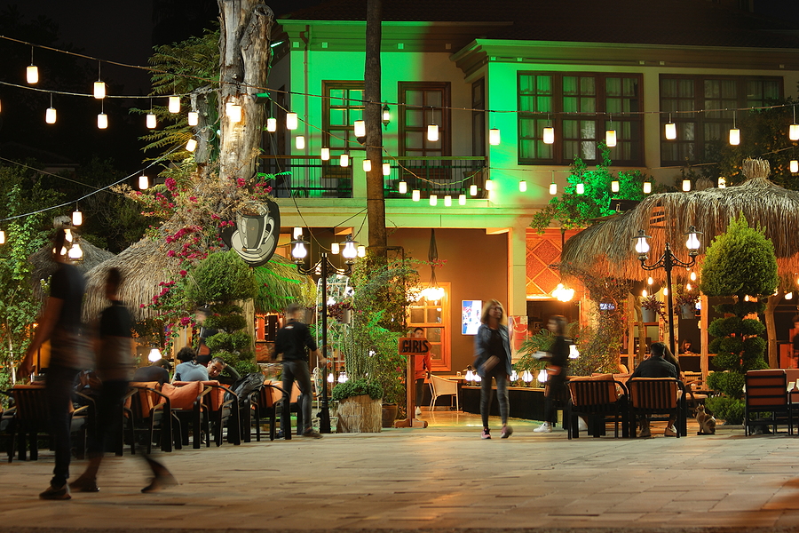 An outdoor restaurant illuminated by warm, inviting lights that create a cozy ambiance and attract customers.