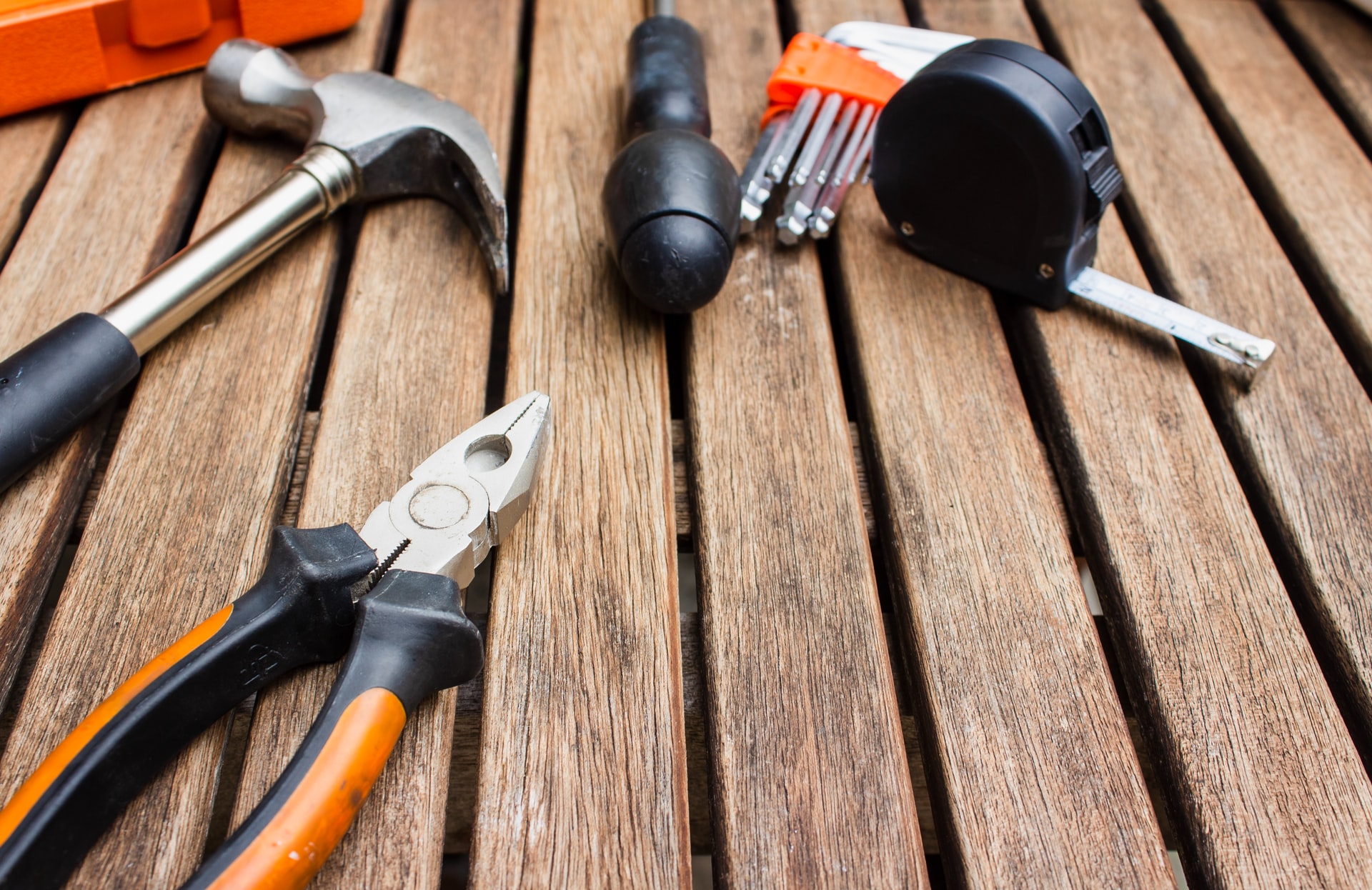 A collection of construction tools arranged on a wooden background, representing the specialized tools and techniques needed for outdoor lighting maintenance.
