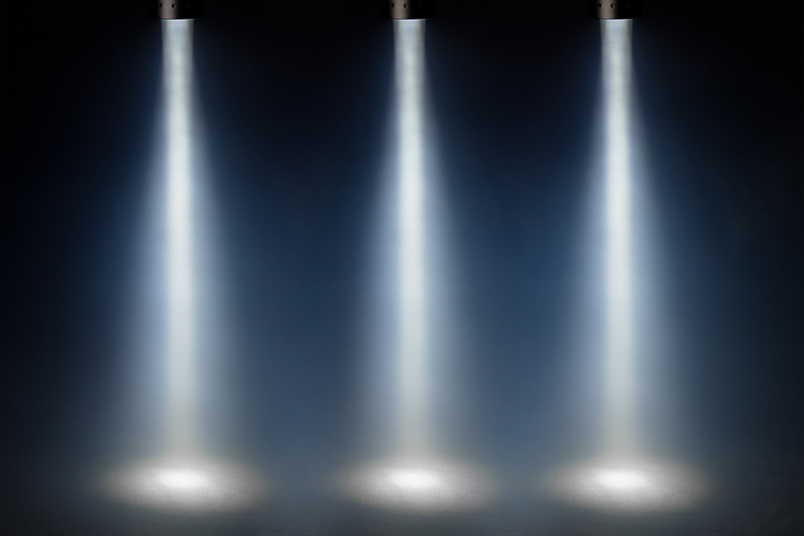 Three blue spotlights shine on a stage, demonstrating the Rule of Three in lighting design for a visually balanced and engaging effect.