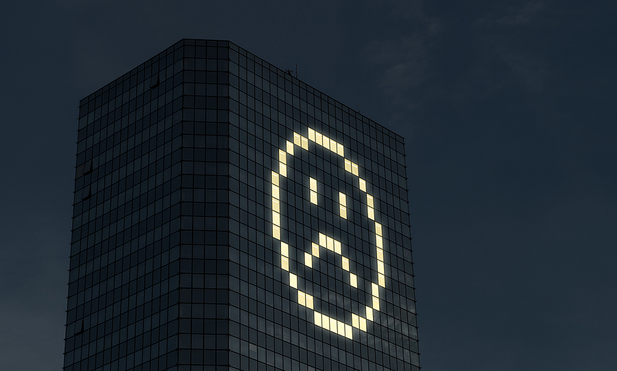 Office building at night with window lights forming a sad face, symbolizing Commercial Lighting.