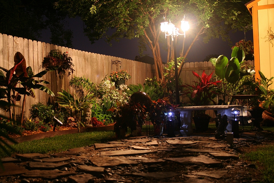 Small backyard view with paved patio, plants, and outdoor seating area.