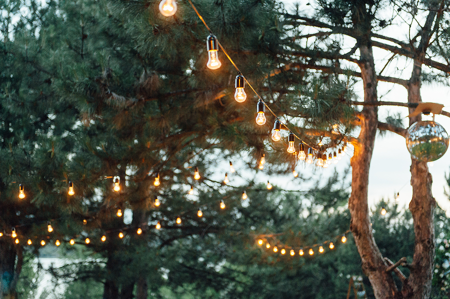String lights hanging at an outdoor party, creating a warm and festive atmosphere.