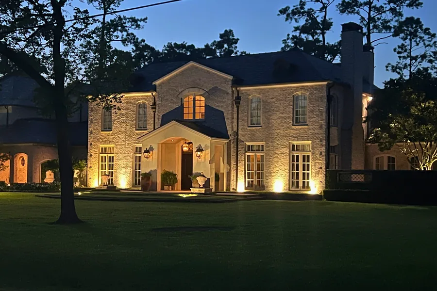 Two-storey home with warm uplighting across the brick and stone elevation