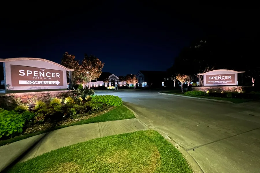 Illuminated monument signs and planting at the entrance to an apartment community