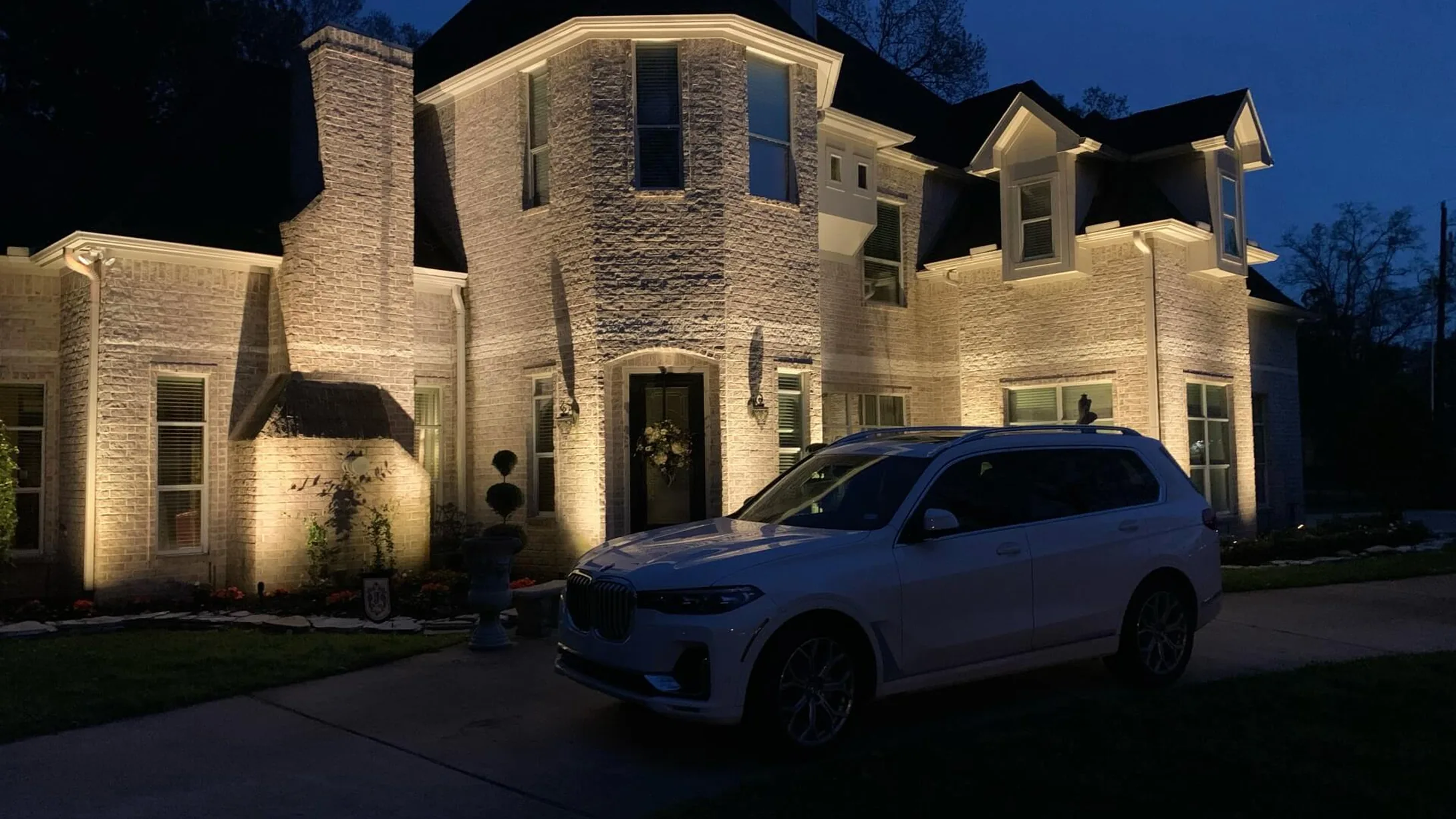 House elevation and drive lit after dark following an outdoor lighting installation
