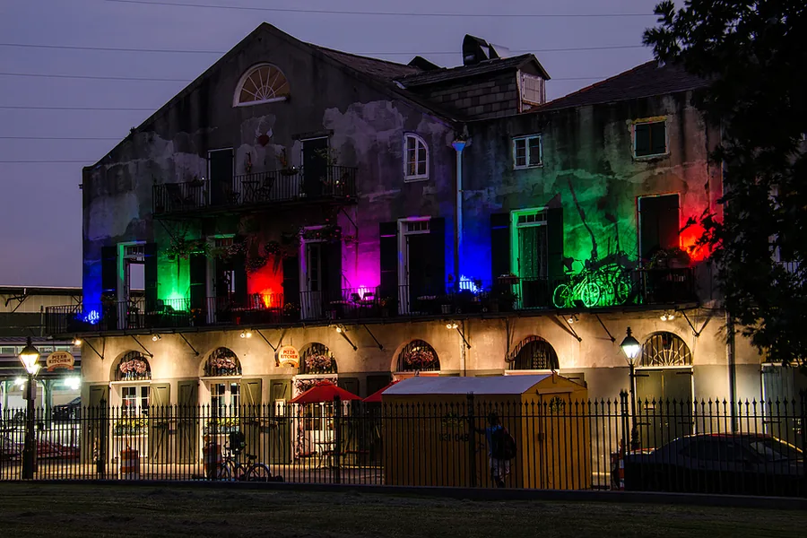 Two-storey building facade washed in colour-changing light after dark