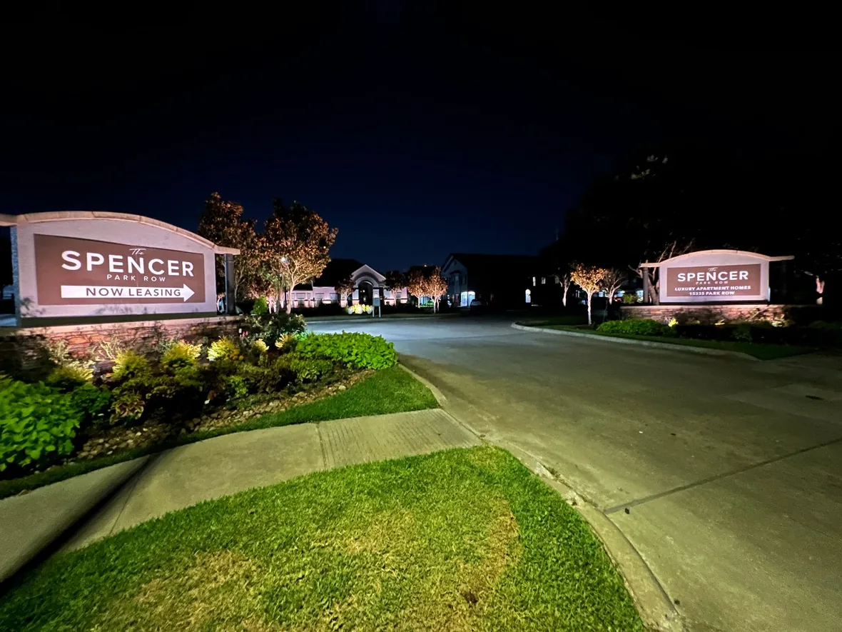 Lit monument sign and planting beds at the entrance to a commercial property