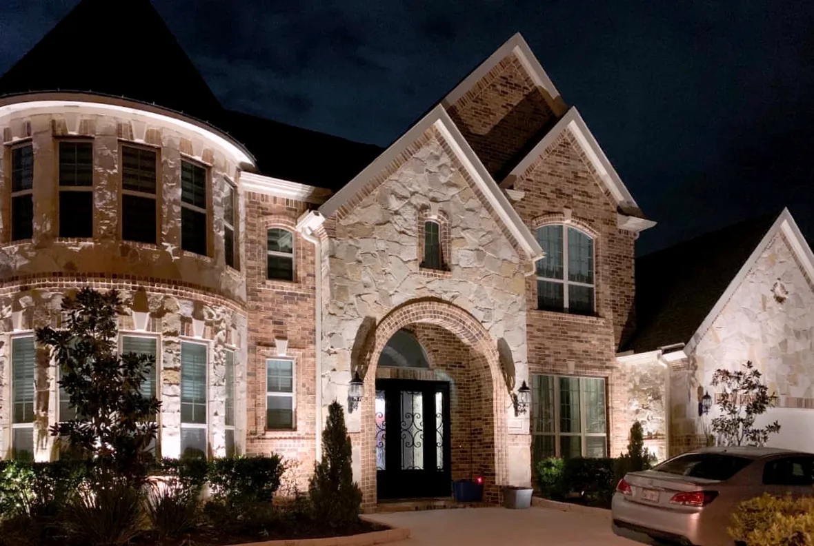 Stone facade and gabled roofline picked out by warm accent lighting after dark