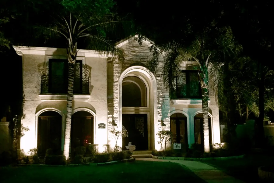 Stone arches and front entrance of a West University home picked out by warm accent lighting