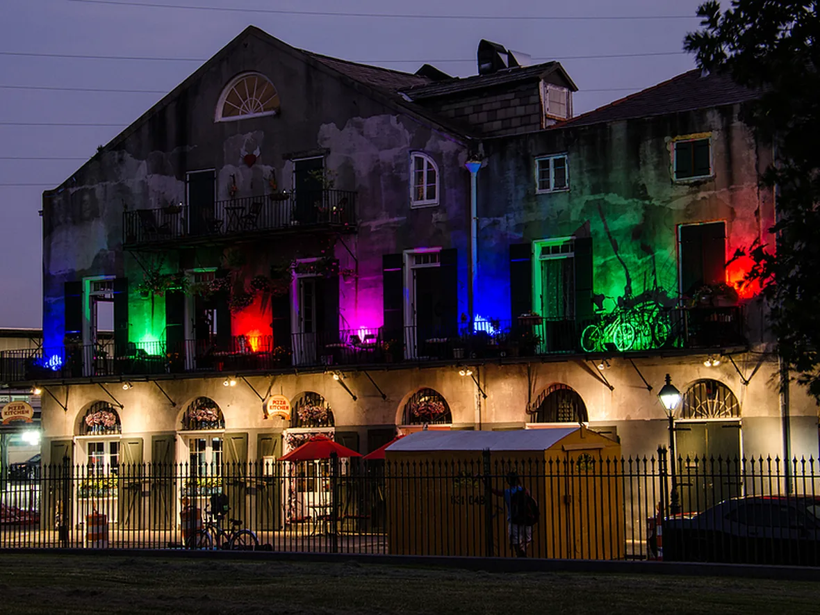 Facade washed in several colours at once for a holiday, with the architecture still legible underneath